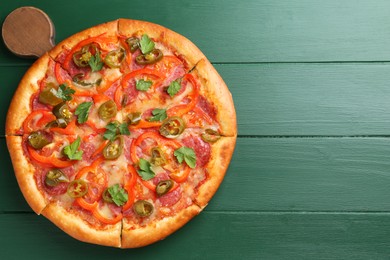 Photo of Delicious pizza Diablo on green wooden table, top view. Space for text