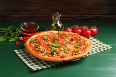 Photo of Delicious pizza Diablo and ingredients on green wooden table