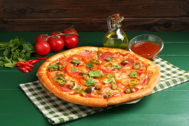 Photo of Delicious pizza Diablo and ingredients on green wooden table