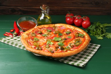 Photo of Delicious pizza Diablo and ingredients on green wooden table