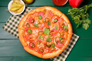 Photo of Delicious pizza Diablo and ingredients on green wooden table, flat lay