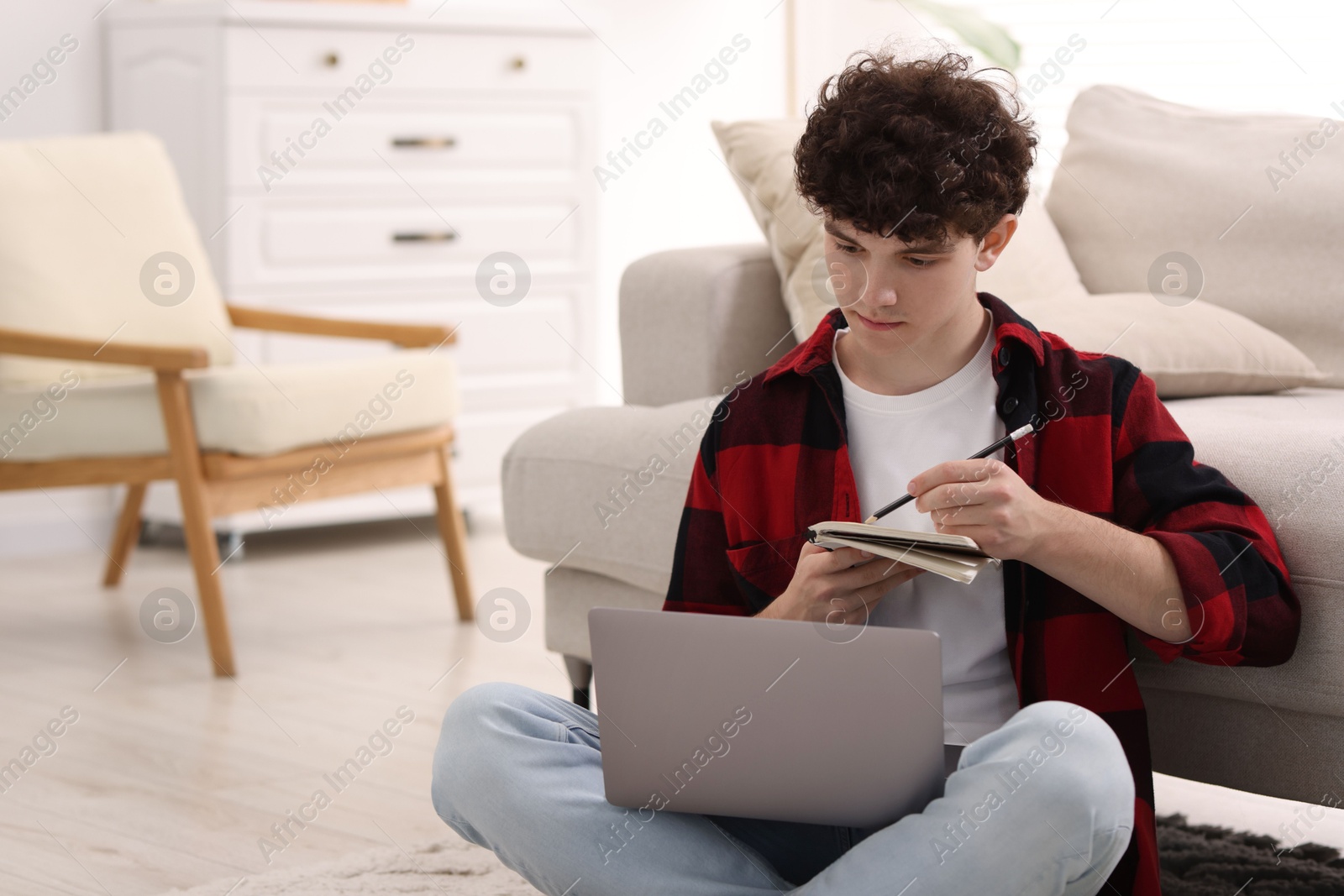 Photo of Teenager taking notes while working with laptop at home, space for text. Remote job