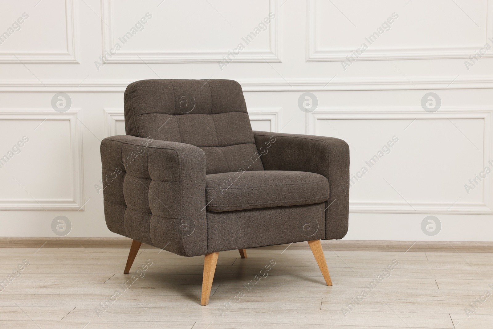 Photo of One soft armchair near white wall indoors