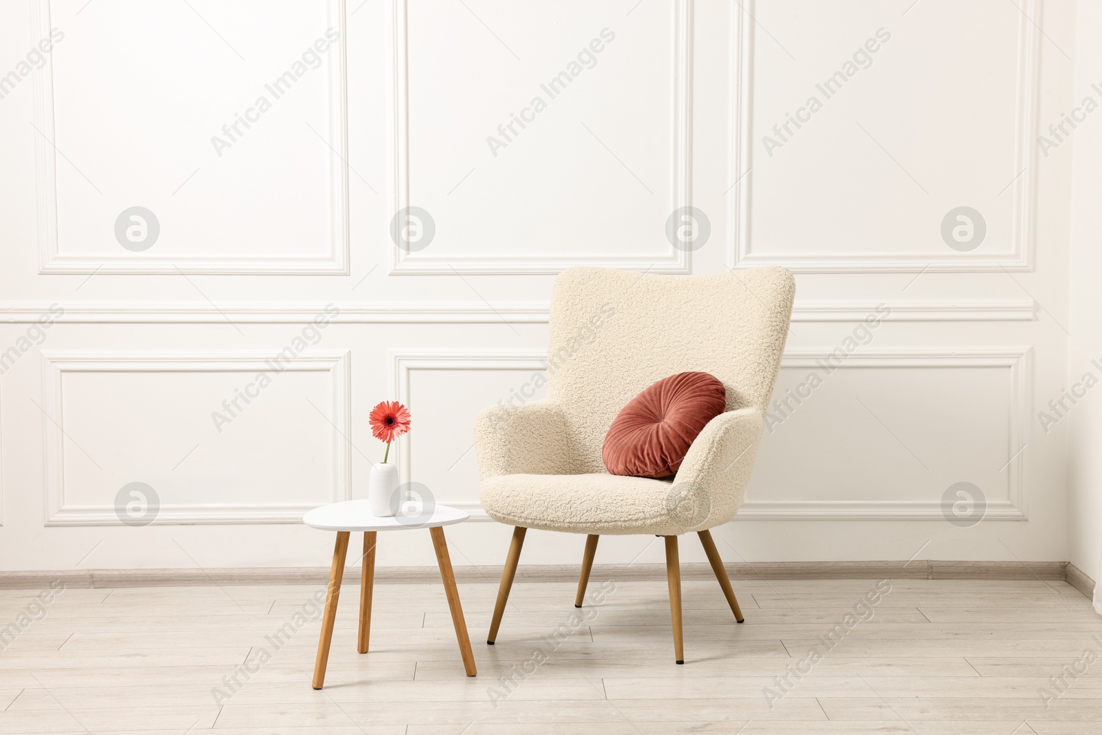 Photo of Soft armchair and coffee table with flower in stylish room