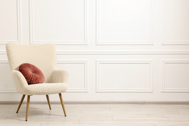 Photo of Soft armchair with pillow in light room. Space for text