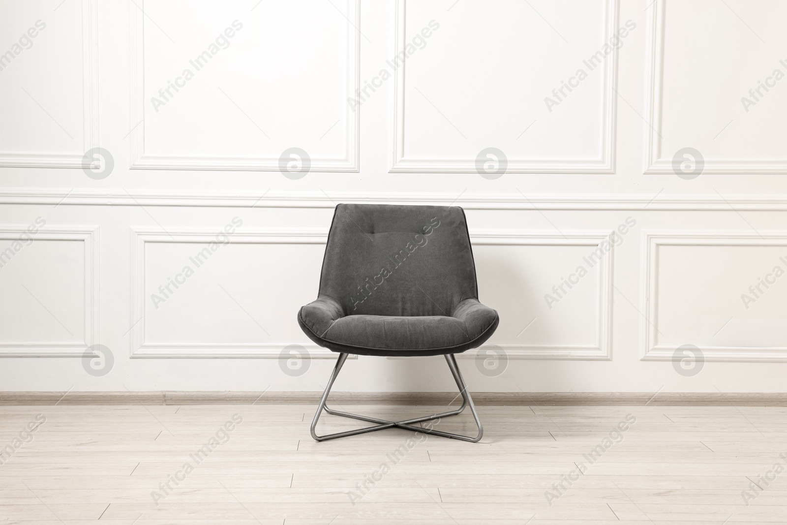 Photo of One soft armchair near white wall indoors