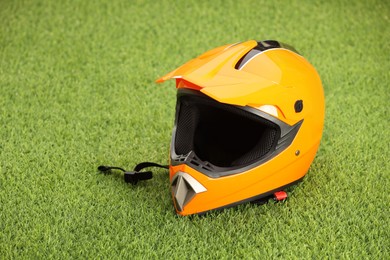 Photo of Orange motorcycle helmet with visor on green grass, space for text