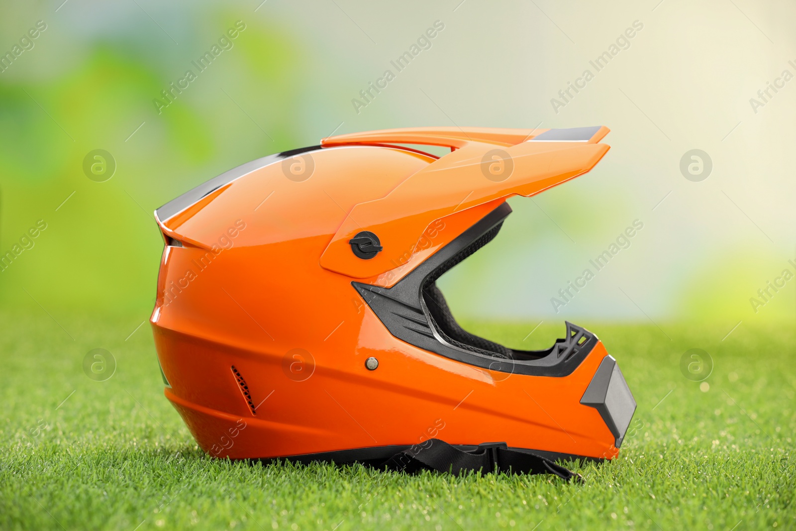 Photo of Orange motorcycle helmet with visor on green grass