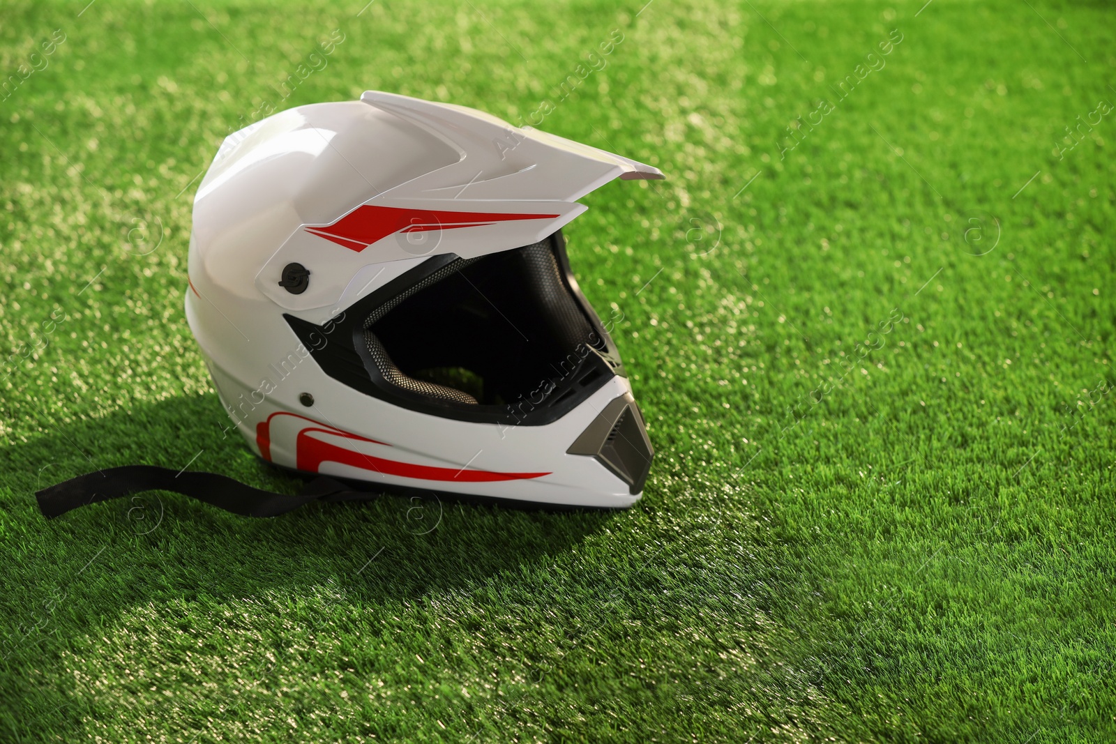 Photo of Modern motorcycle helmet with visor on green grass, space for text