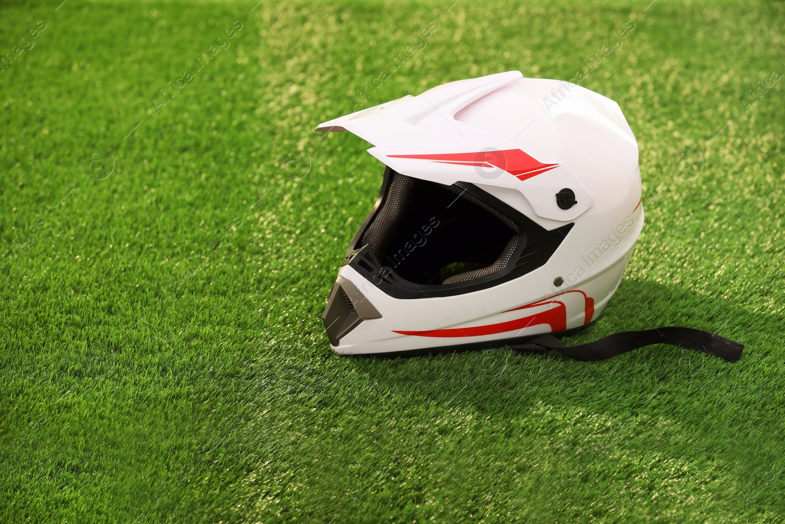 Photo of Modern motorcycle helmet with visor on green grass, space for text