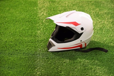 Modern motorcycle helmet with visor on green grass, space for text