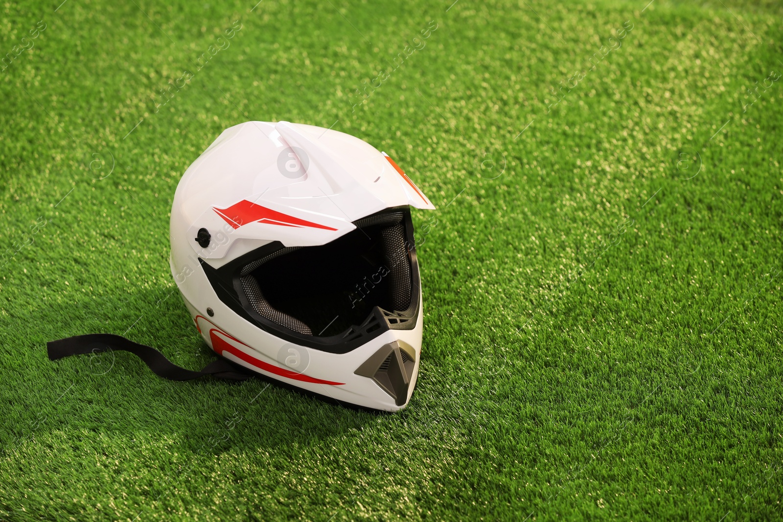 Photo of Modern motorcycle helmet with visor on green grass, space for text