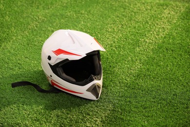 Photo of Modern motorcycle helmet with visor on green grass, space for text