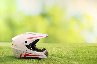 Photo of Modern motorcycle helmet with visor on green grass, space for text