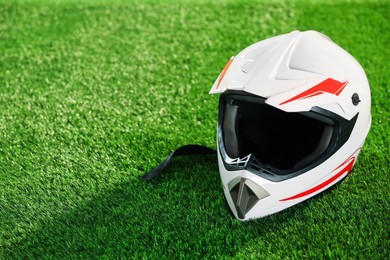 Photo of Modern motorcycle helmet with visor on green grass, space for text