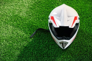 Photo of Modern motorcycle helmet with visor on green grass, space for text