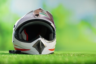 Photo of Modern motorcycle helmet with visor on green grass, space for text