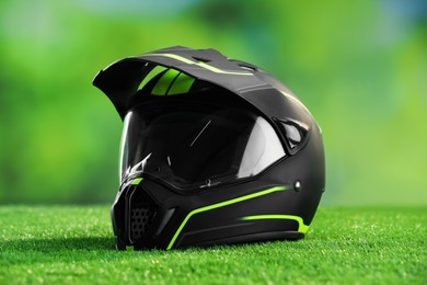 Photo of Modern motorcycle helmet with visor on green grass