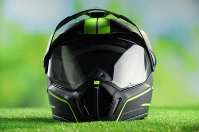 Photo of Modern motorcycle helmet with visor on green grass, closeup