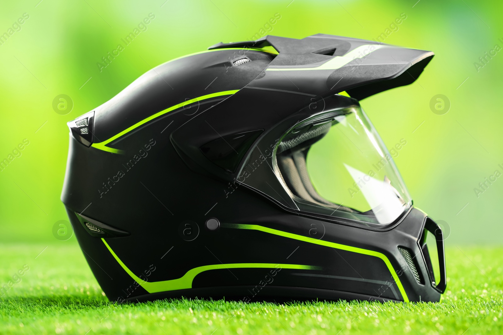 Photo of Modern motorcycle helmet with visor on green grass