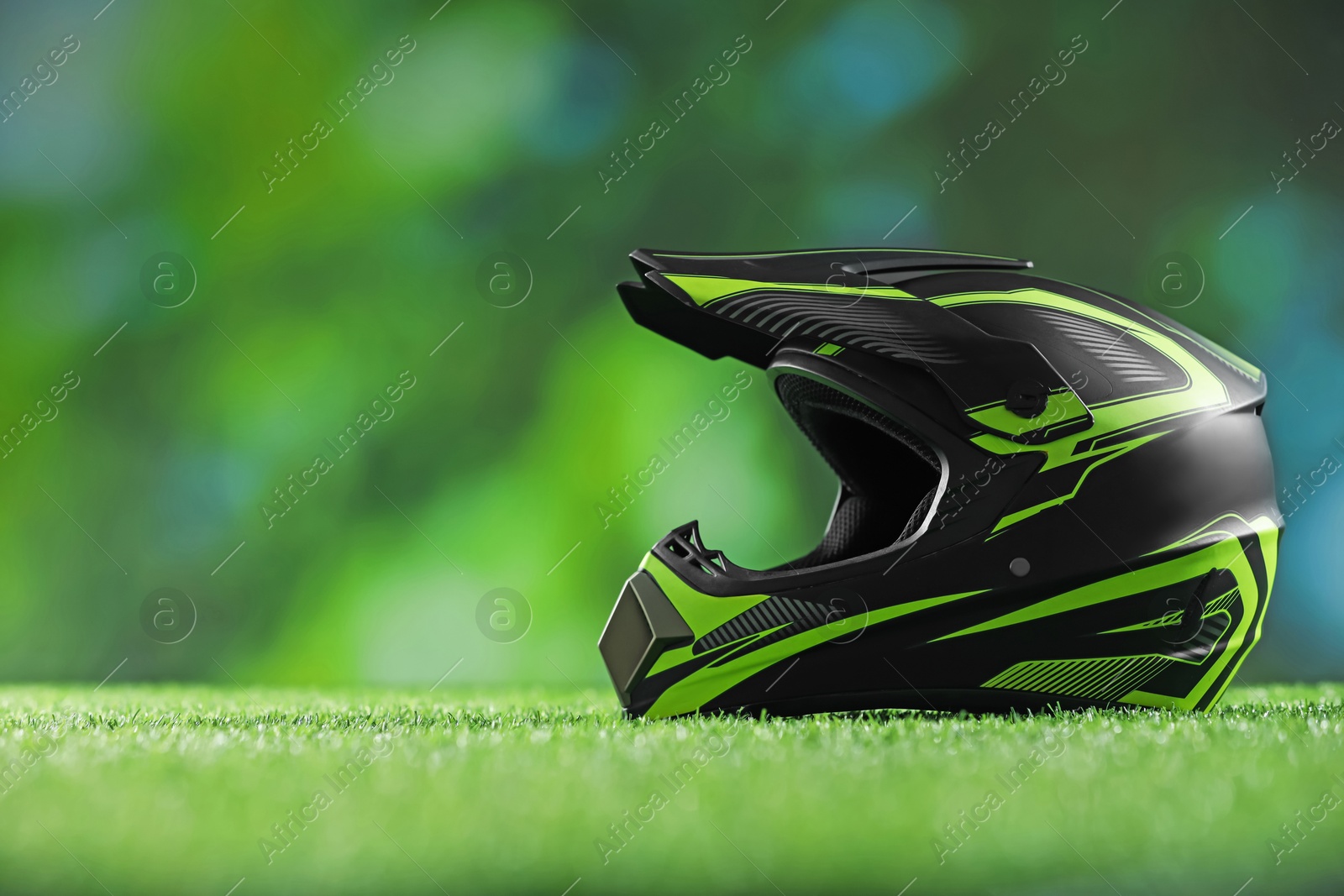 Photo of Modern motorcycle helmet with visor on green grass, space for text