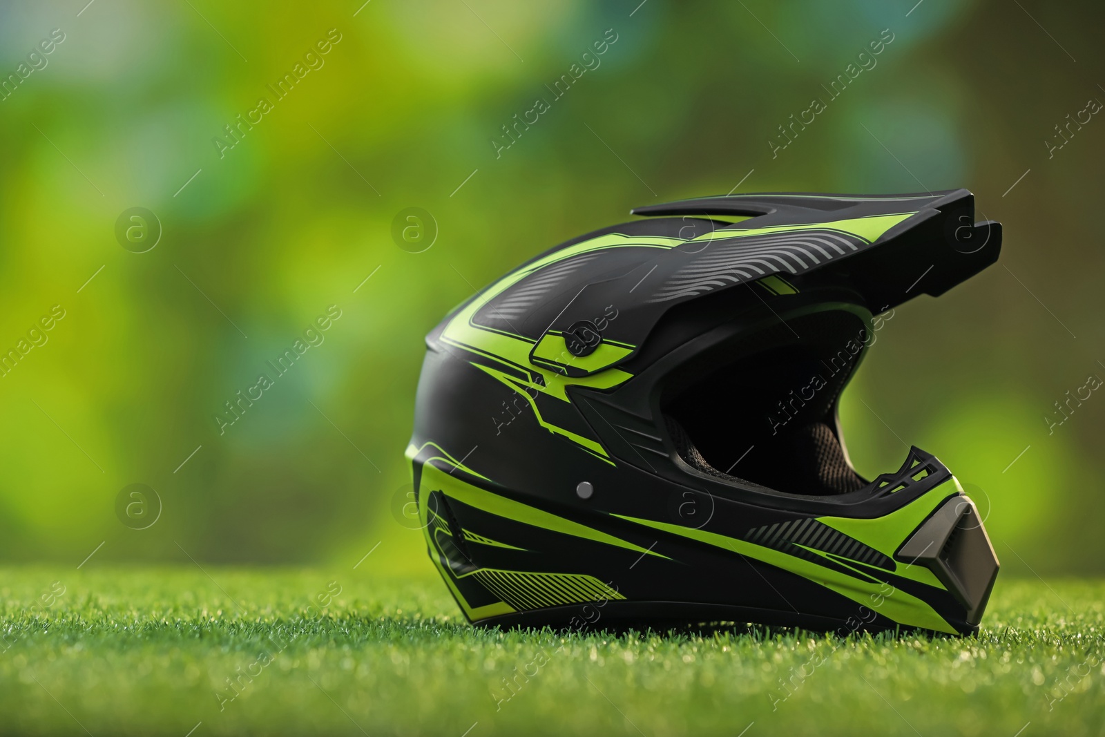 Photo of Modern motorcycle helmet with visor on green grass, space for text