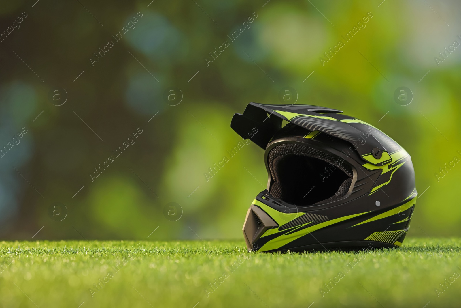 Photo of Modern motorcycle helmet with visor on green grass, space for text