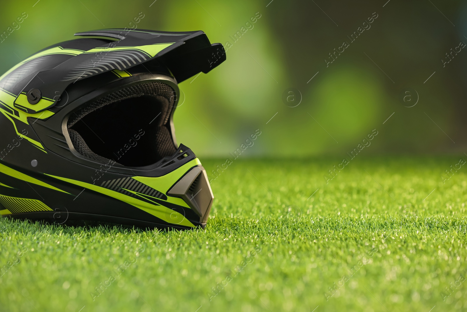 Photo of Modern motorcycle helmet with visor on green grass, space for text