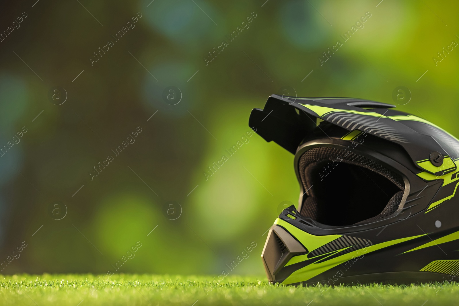 Photo of Modern motorcycle helmet with visor on green grass, space for text