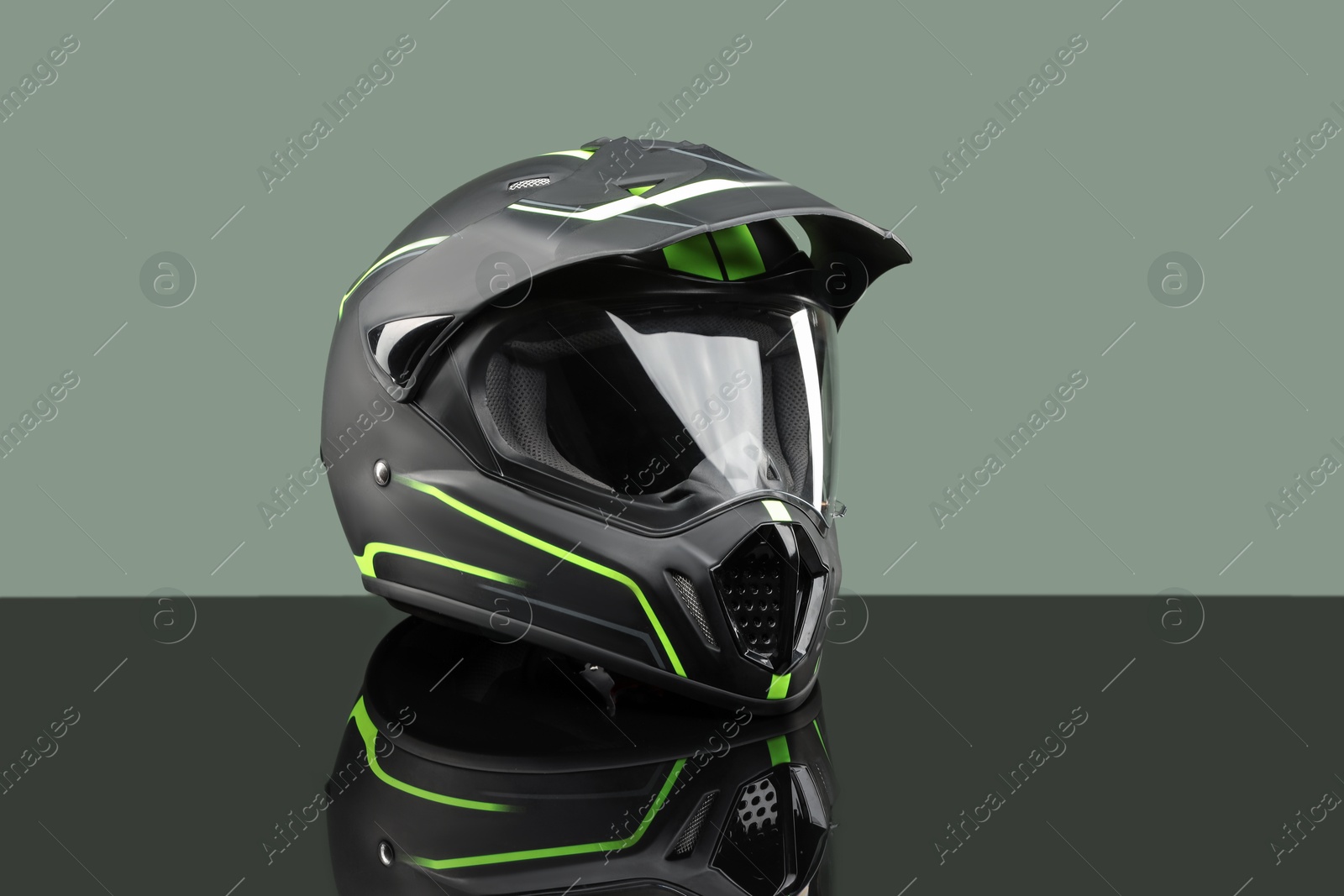 Photo of Modern motorcycle helmet with visor on mirror surface against light grey background