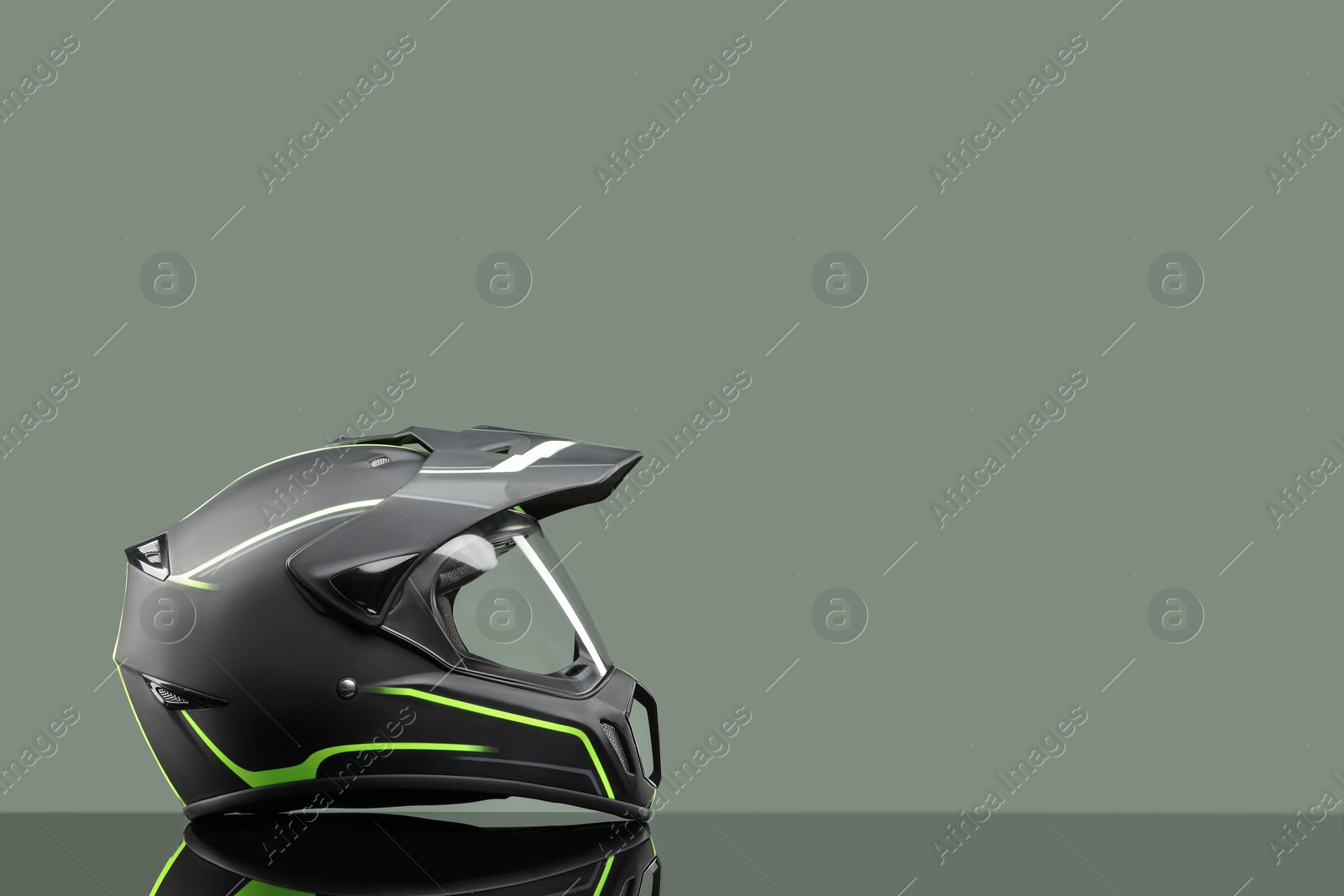 Photo of Modern motorcycle helmet with visor on mirror surface against light grey background. Space for text