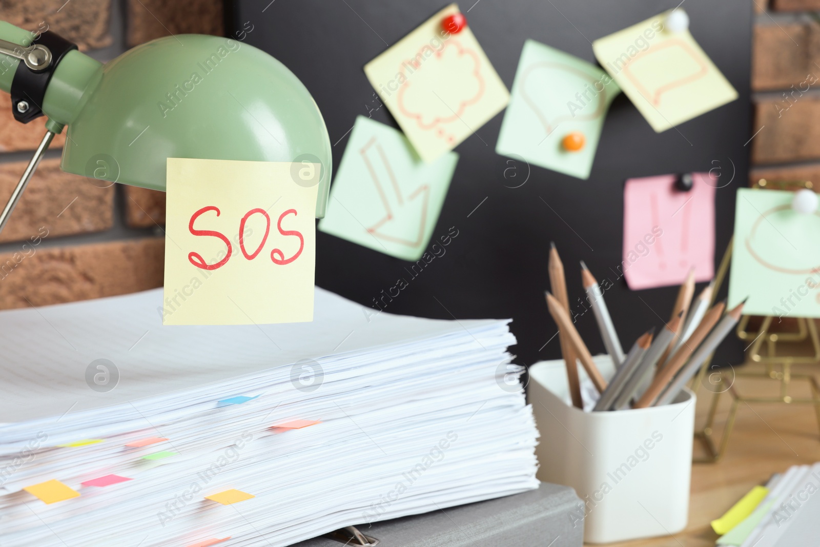 Photo of Sticky note with word SOS on lamp at workplace