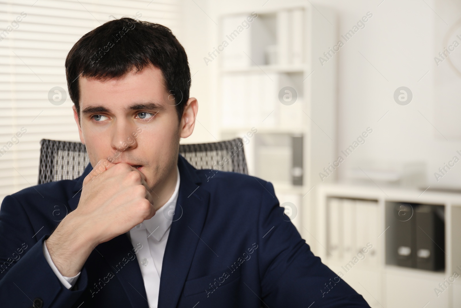Photo of Portrait of embarrassed young man in office. Space for text