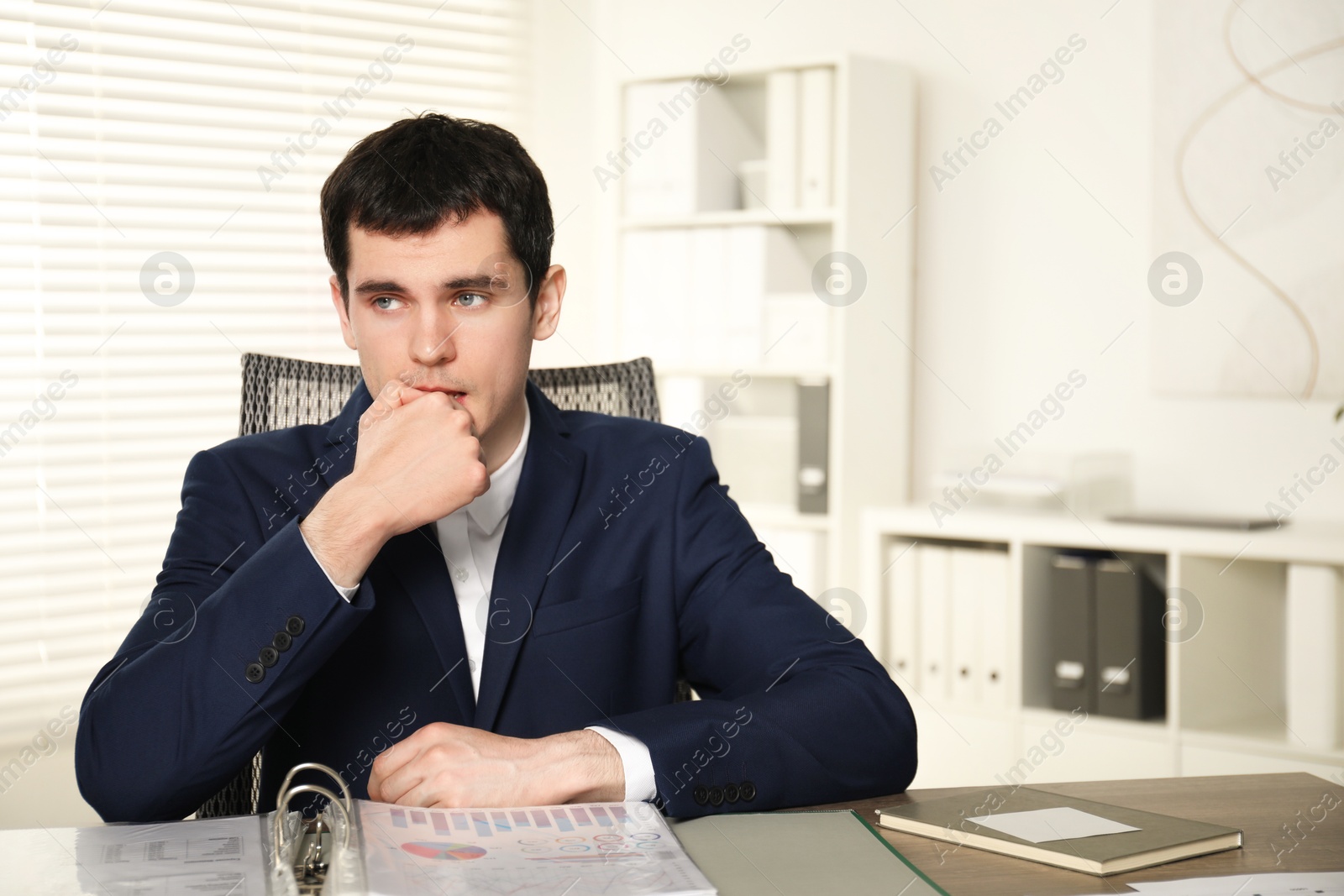 Photo of Embarrassed man at table with documents in office. Space for text