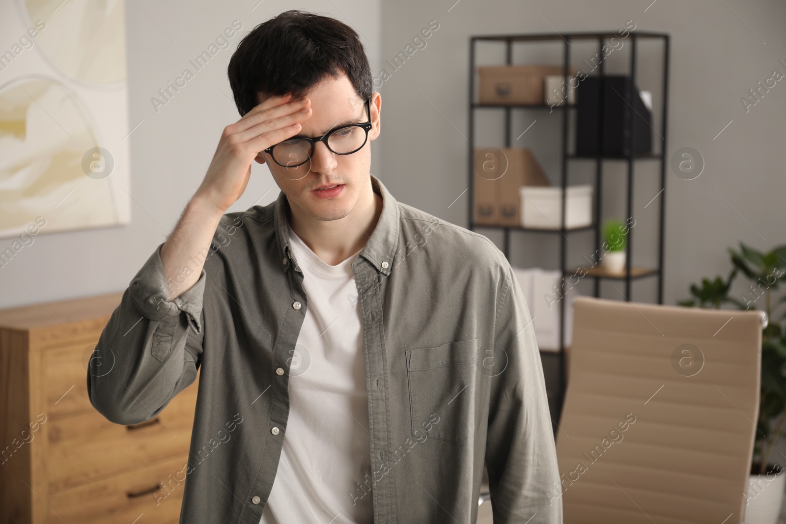 Photo of Embarrassed young man in glasses in office