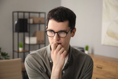 Photo of Embarrassed young man in glasses in office