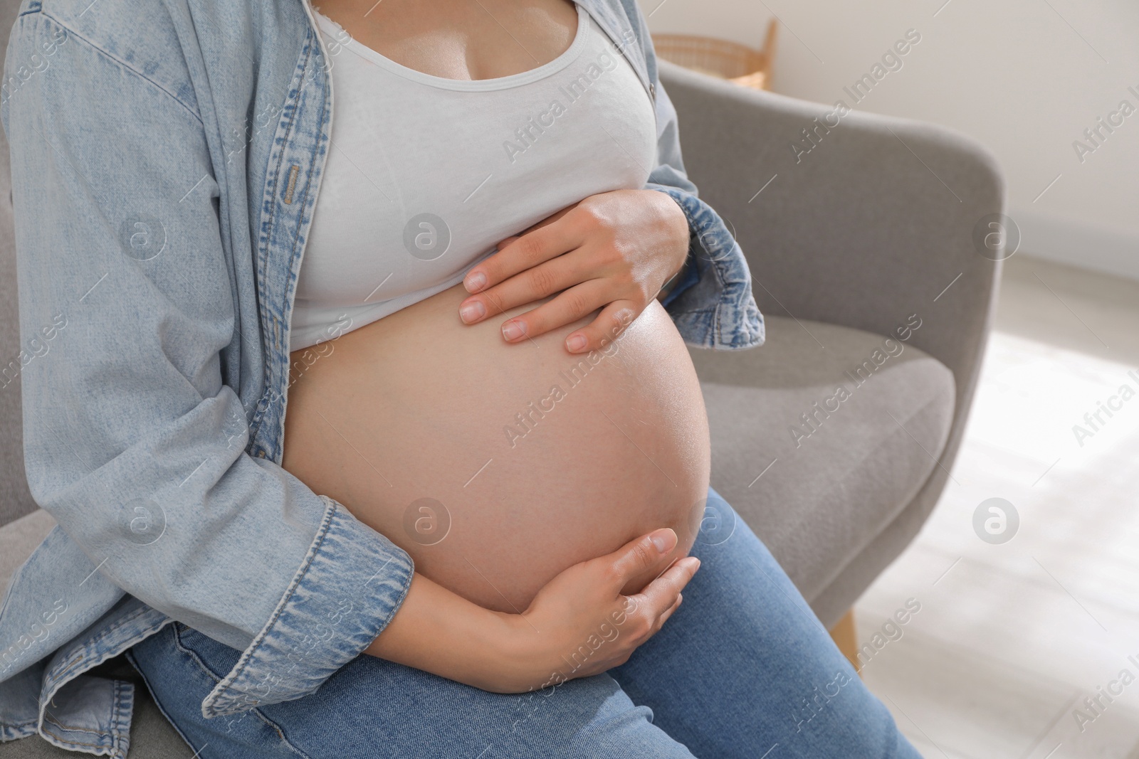 Photo of Pregnant woman sitting on sofa at home, closeup