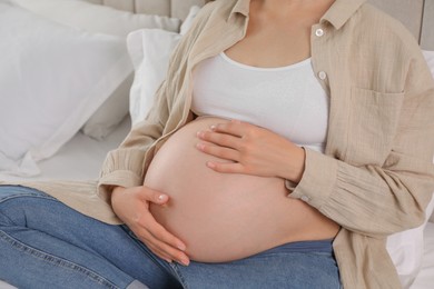 Pregnant woman on bed at home, closeup