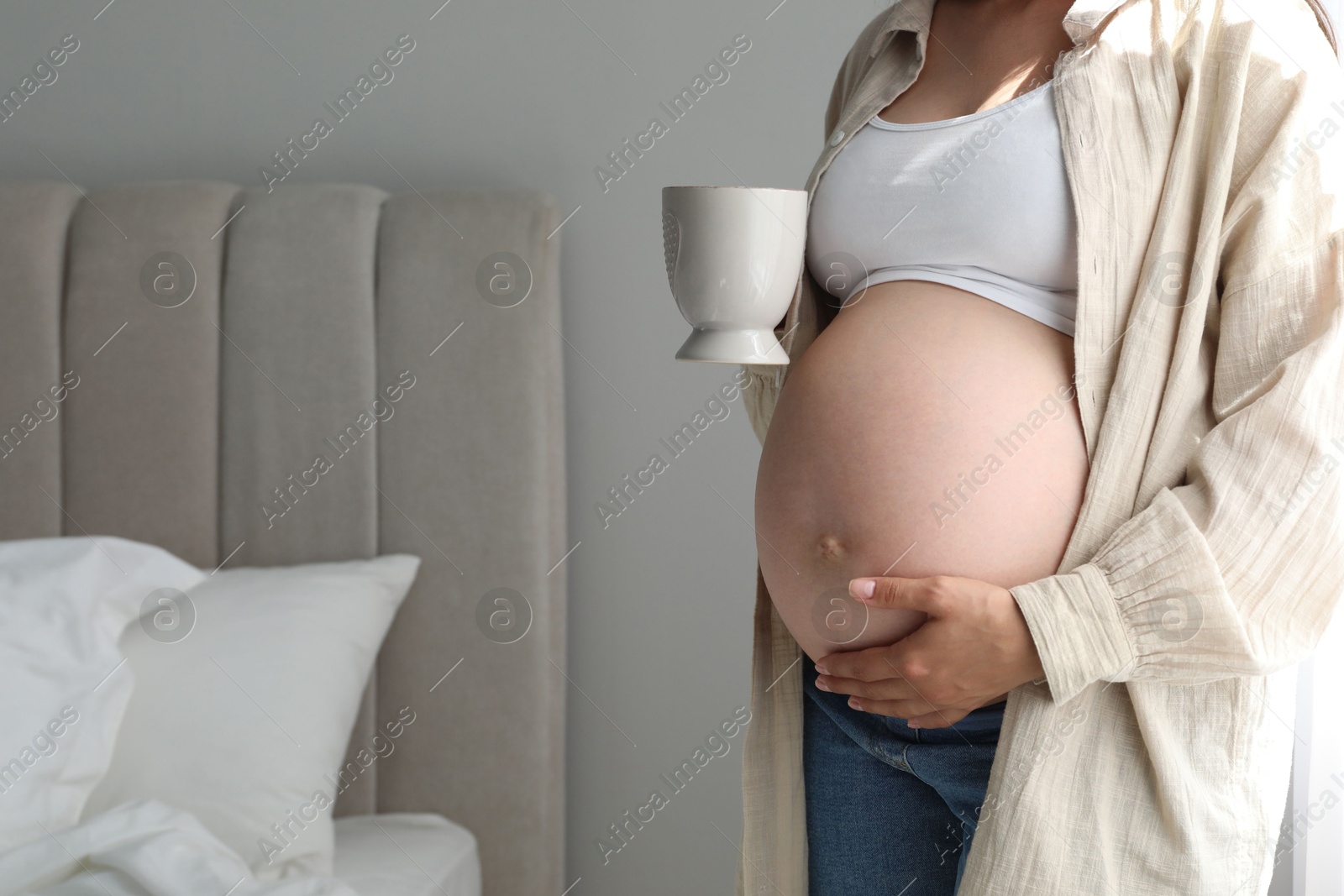 Photo of Pregnant woman with cup at home, closeup