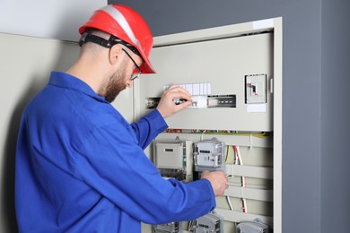 Photo of Electrician wearing uniform installing electricity meter indoors