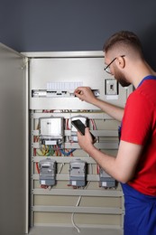 Photo of Technician worker with smartphone inspecting electricity meter