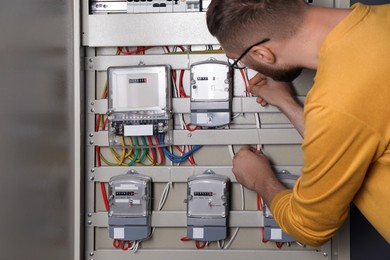 Photo of Man checking electricity meter indoors, closeup view