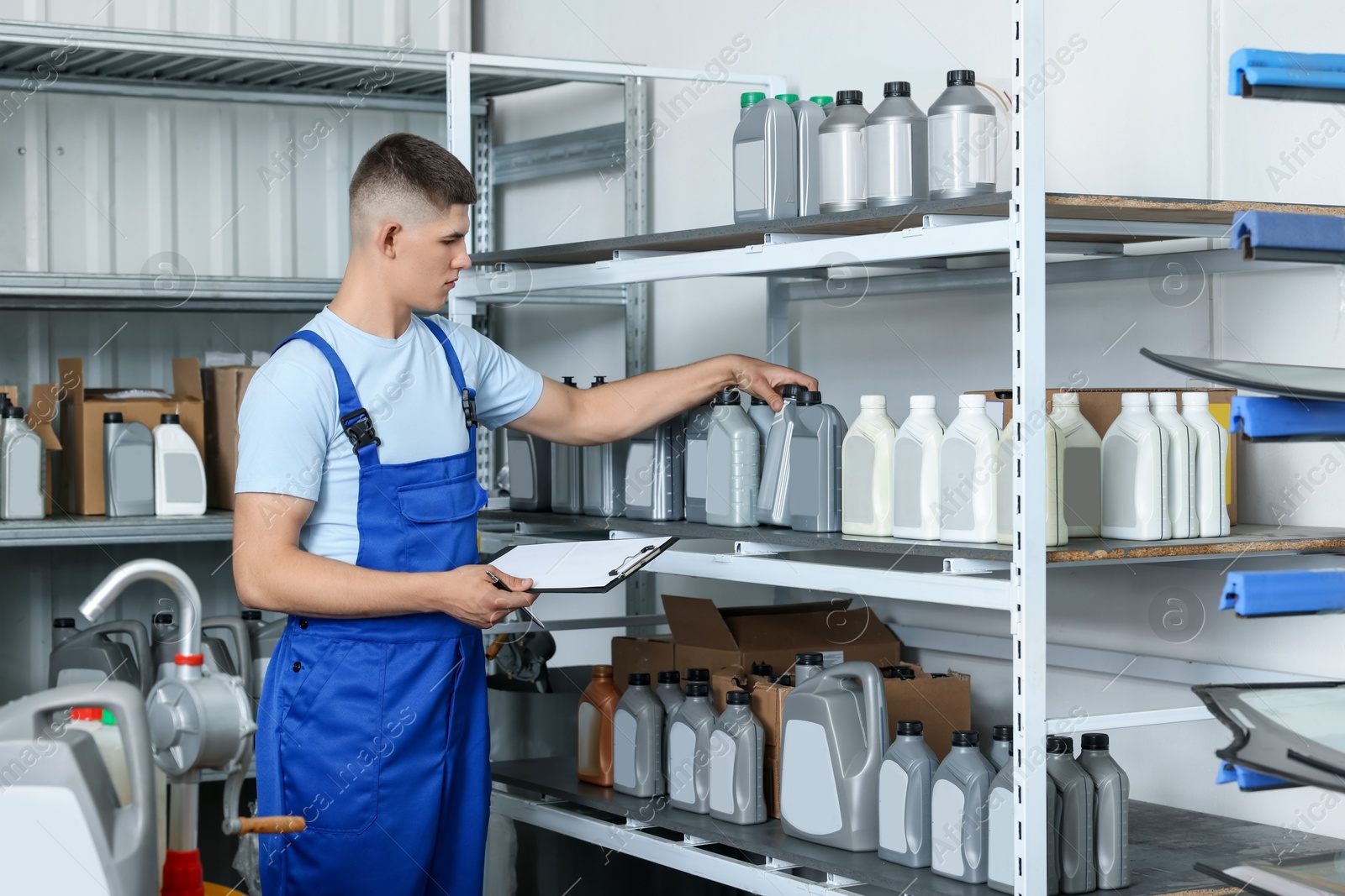 Photo of Man with clipboard and different car products in auto store