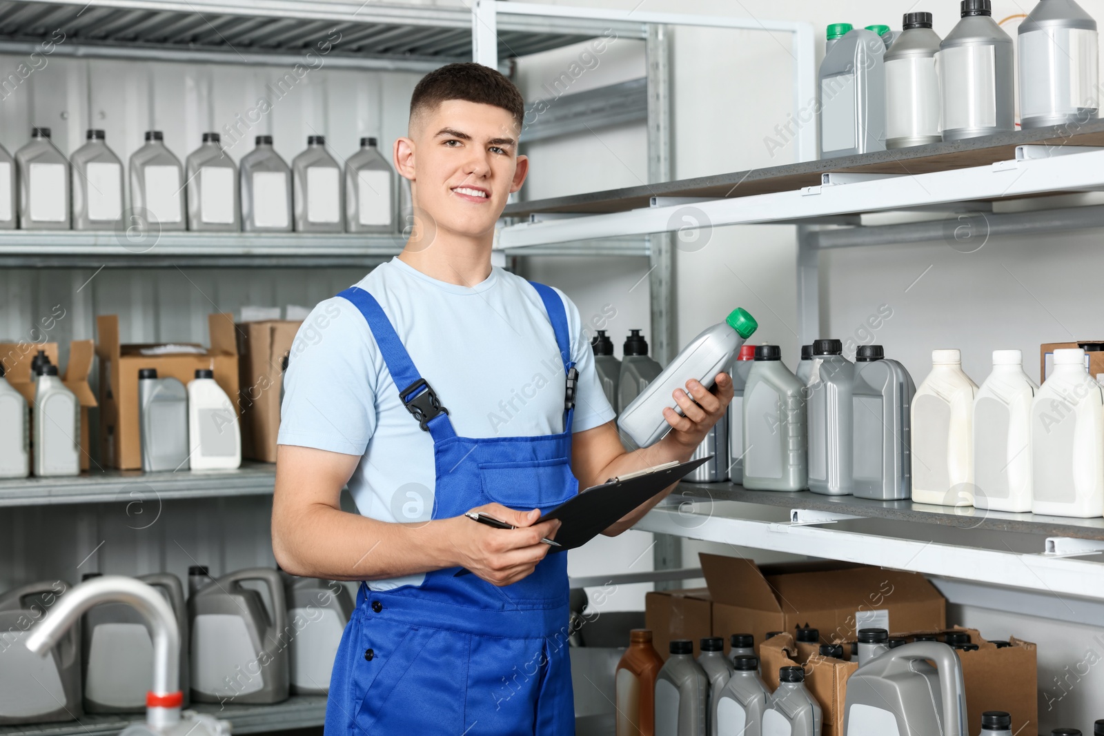 Photo of Smiling young man with clipboard and different car products in auto store