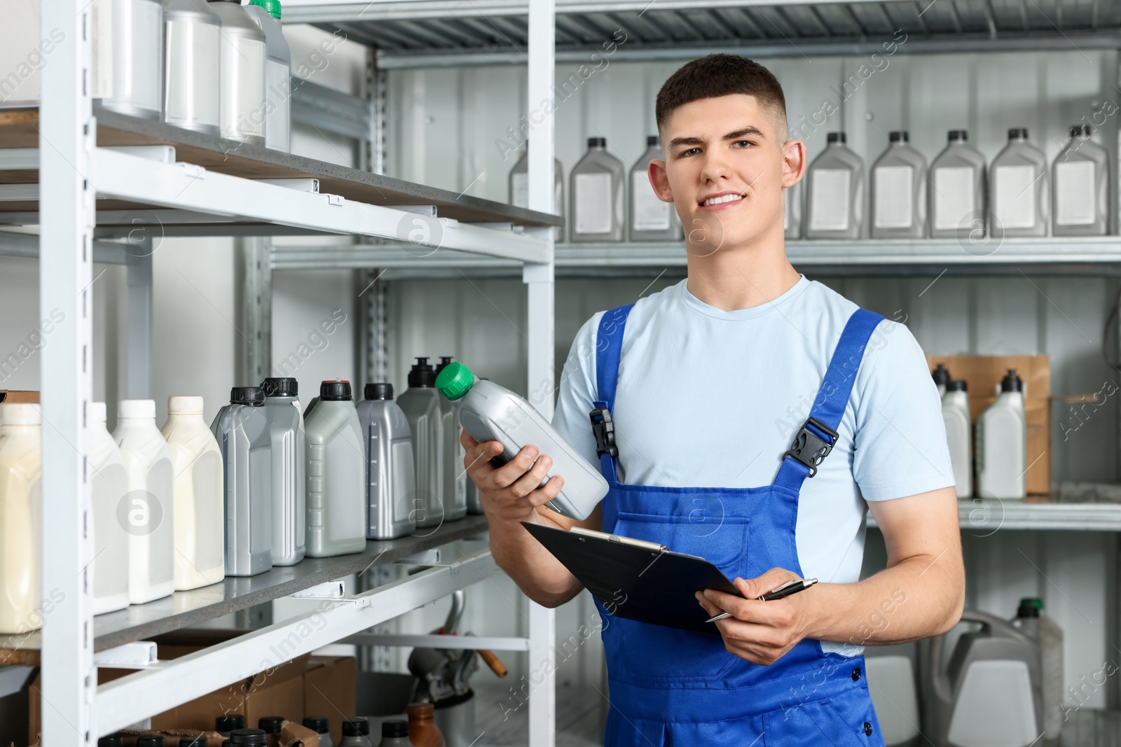 Photo of Smiling young man with clipboard and different car products in auto store