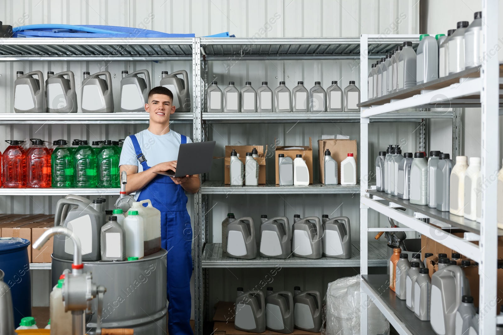 Photo of Smiling young man with laptop and different car products in auto store