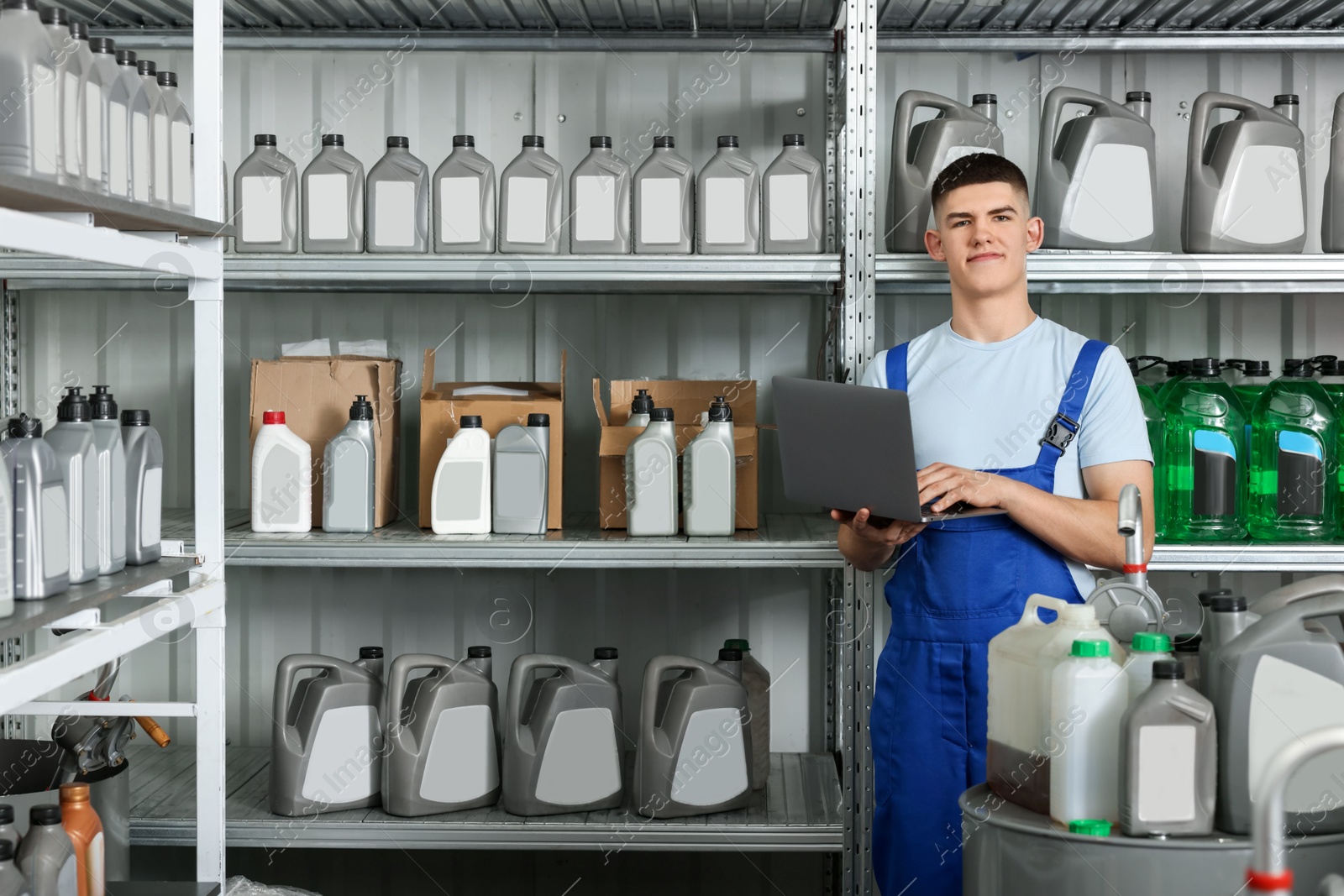 Photo of Young man with laptop and different car products in auto store