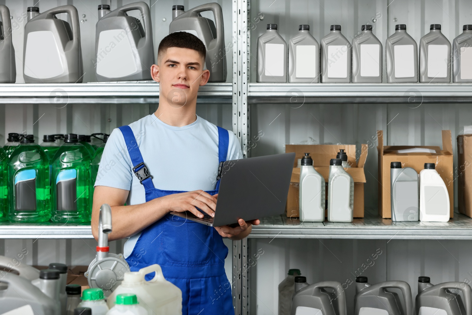 Photo of Young man with laptop and different car products in auto store