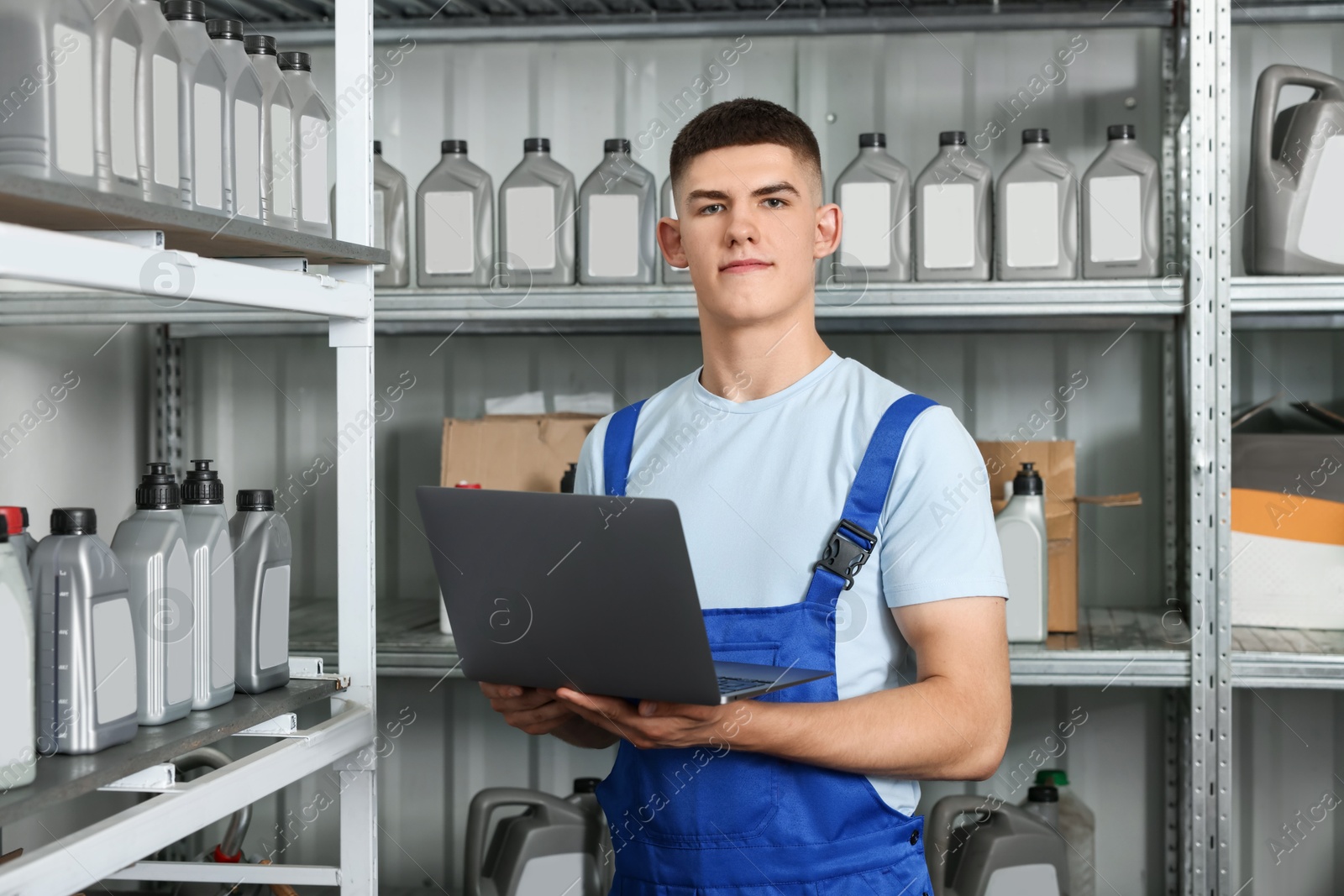 Photo of Young man with laptop and different car products in auto store