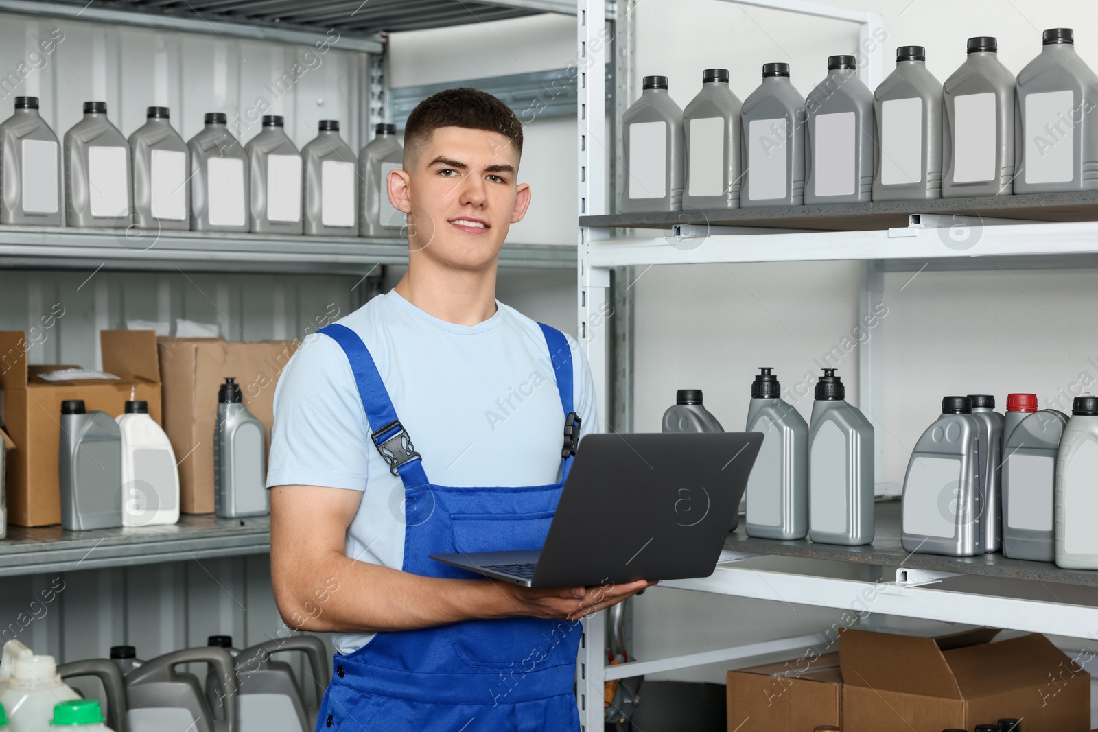 Photo of Smiling young man with laptop and different car products in auto store